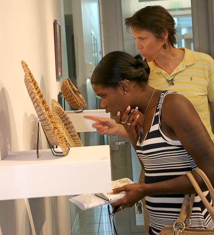 Professor Lucy Snow (rear) and student Jessica Walters admire Kathryn Nielsen’s basket weaving. 