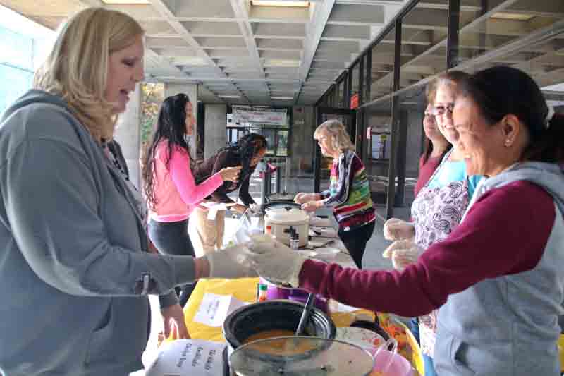 Student Assistant Mylene Lim serves Robin Armour’s “The Whole Enchilada Chicken Soup” to Administrative Assistant Sylvia Benzler during the 5th Annual Soup Cook-Off in the Indoor Quad.
