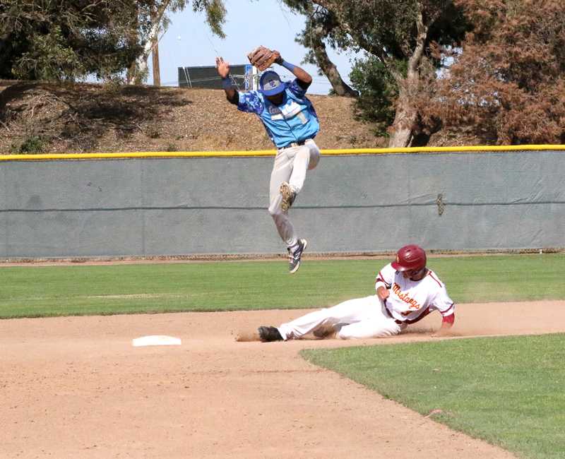 LMC’s Leonard Aue slides into second base safely as CCC’s Antonio Straughter leaps in the air and misses the out. 