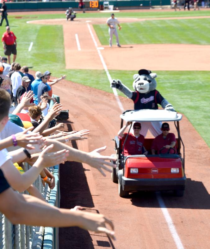 Fans reach out for Sacramento Rivercats mascot Dinger as he rolls around the park delivering gifts and collectibles in between innings.