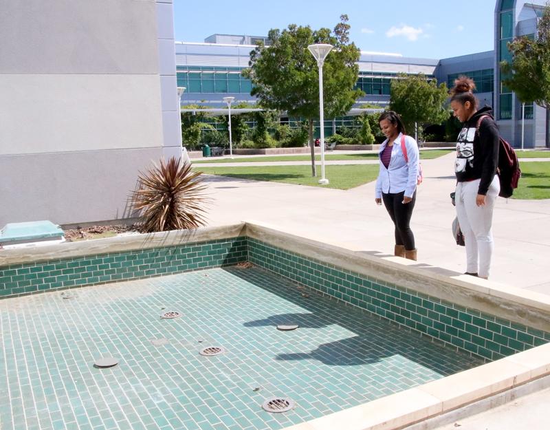 Students Shaniquia McCoy (left) and Tyisha Blackmon gaze into the dry fountain located outside the library. 