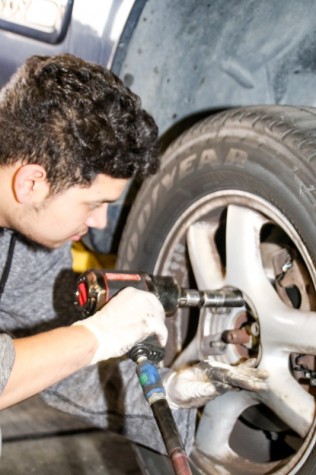 LMC Automotive, December 2, 2015. Brake day is wednesday at LMC, Rene Ayala is putting lug nuts back on to the tire. Cathie Lawrence/Experience.