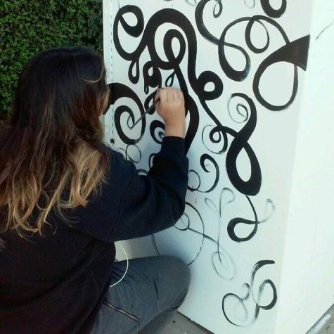 Gomez painting the side of her utility box.