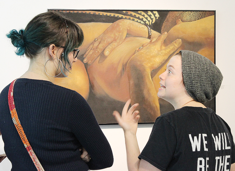 Los Medanos College students Ashley Martinez and Gianna Di Ricco engage over Ken Alexanders painting titled Eve during the Art Show Reception Thursday Sept. 7.