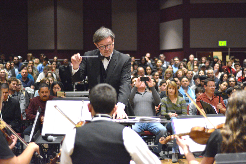 Heritage High School music director Steve Ernest conducts band students as audience members watch.