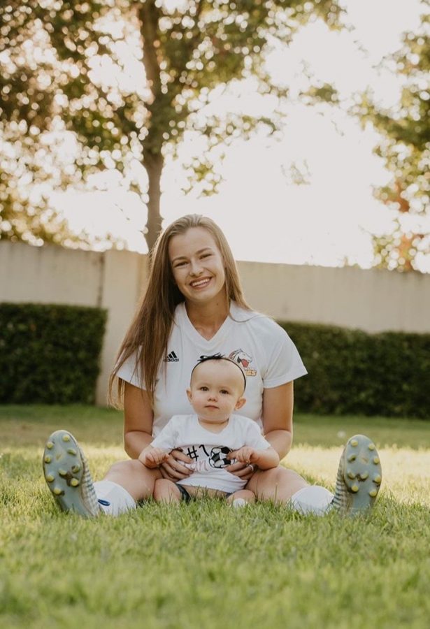 Carissa sits in grass with her daughter, Reese.