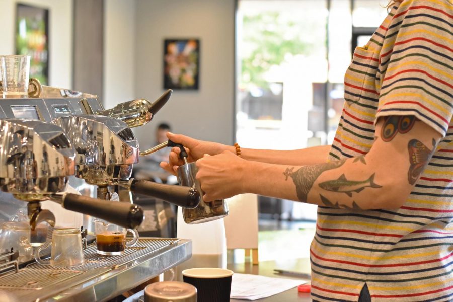 Barista steams a latte behind the counter at Big House beans. 