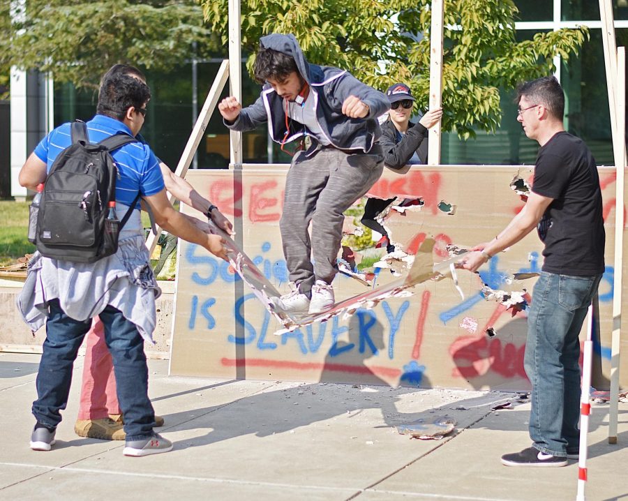 Aadil Faith smashes through a segment of Young Americans for Freedoms Berlin Wall. 