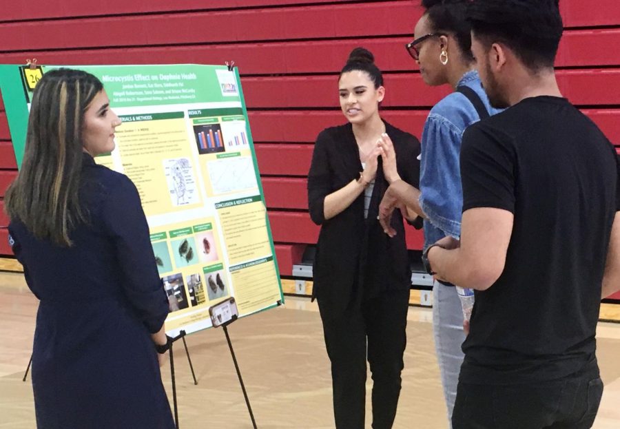 Sana Saleem (left) and Kat Elera present their poster about research on Daphnia to students.