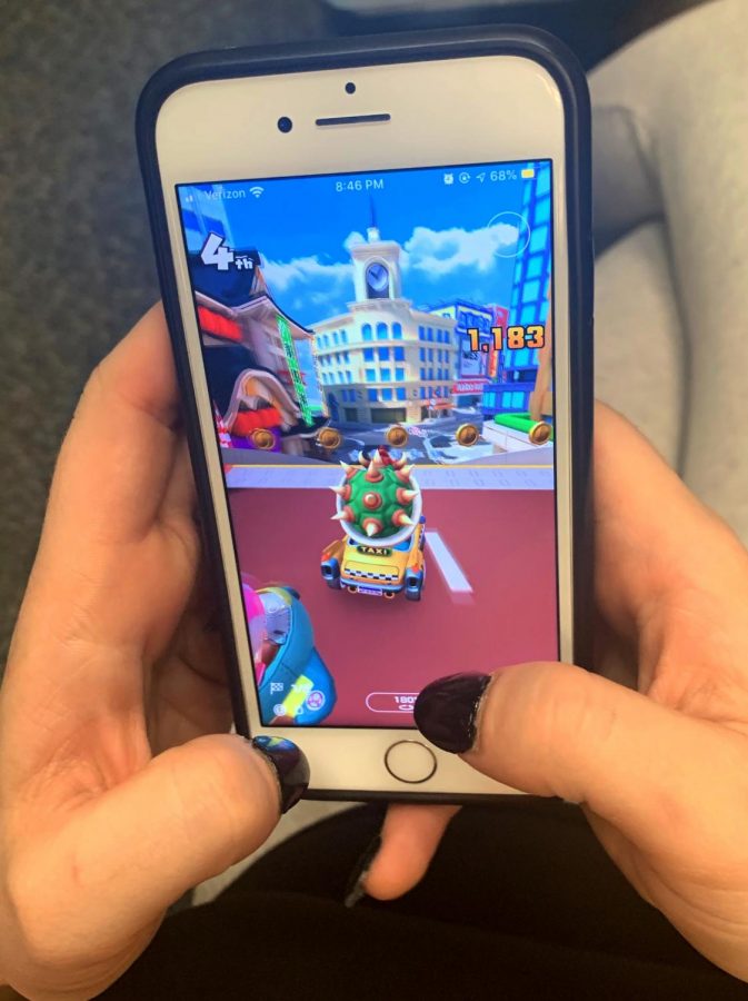 Gamer plays Mario Kart Tour on iPhone, tilting phone and using fingers to control the racing avatar with precision.
