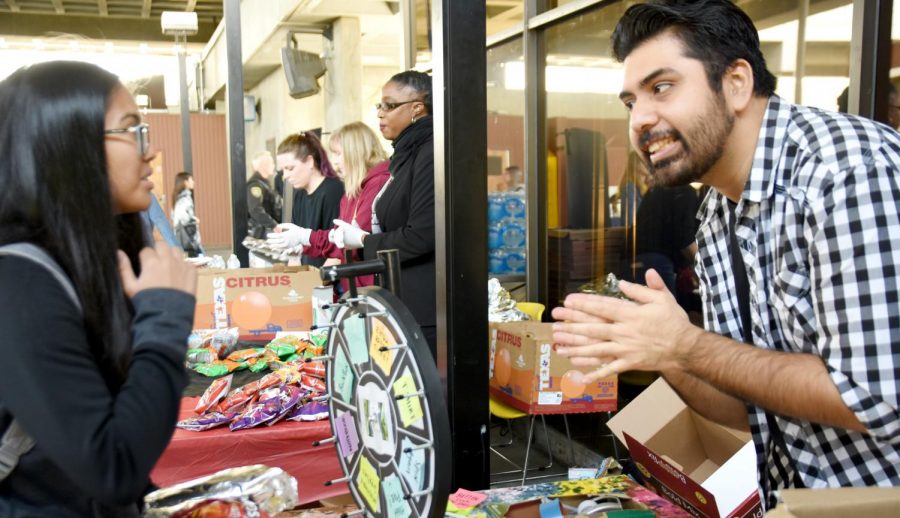 A student interacts with Fabian Ortega (right) before spinning the wheel of prizes during Mustang Day.