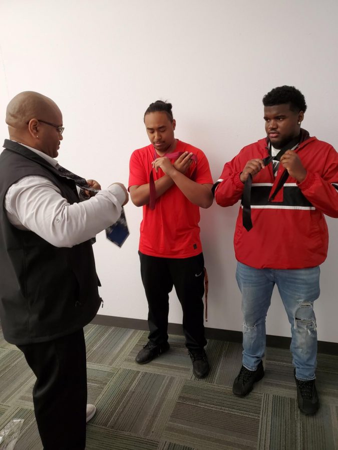 Marques McCoy (left) teaching students Oryon Atualevao (center) and George Mills 3rd how to tie a tie.