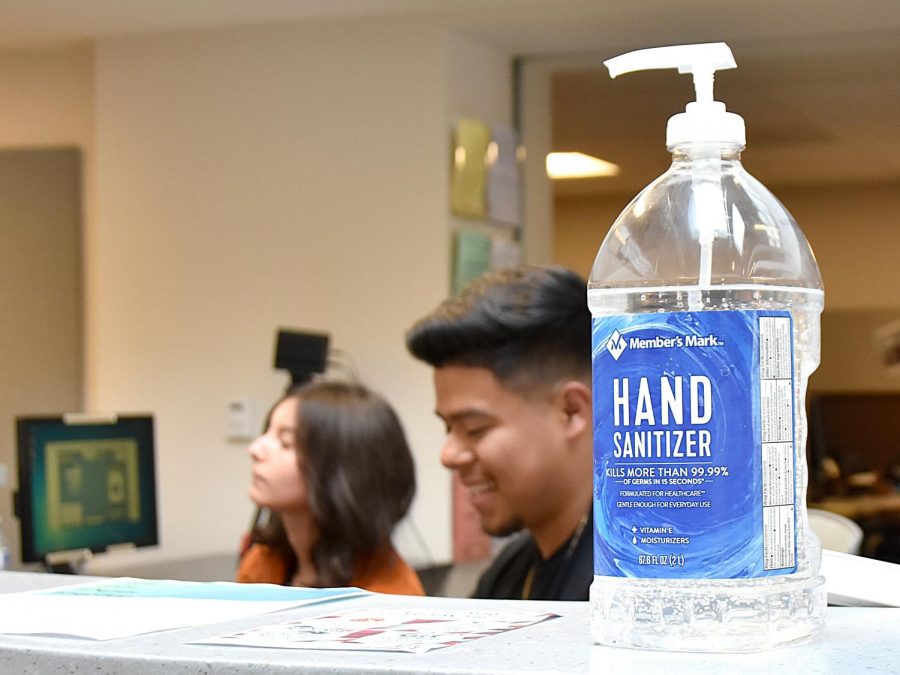 Student workers Jocelyn Villalobos and Richard Preza work at the Information Desk where there is a new hand sanitizer pump for all to use.
