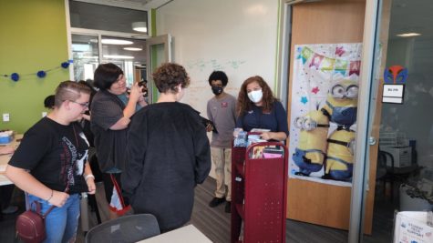 Students and staff gather around with or without masks on