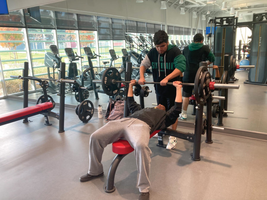 LMC student Osvaldo Ramirez spots fellow student Miguel Lopez lifting weights in the new Kinesiology and Athletics Complex