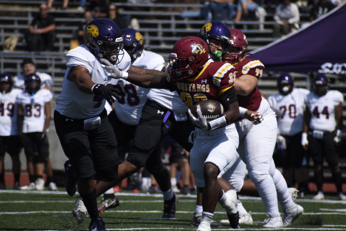Los Medanos College Mustangs running back Aikiz King stiff arms an opponent looking to run past him and gain yards.