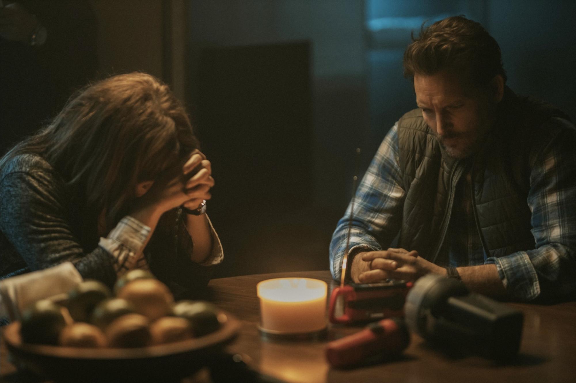 Dave Laughlin, portrayed by Peter Facinelli, and Sarah Laughlin, portrayed by Fiona Dourif, sitting at a table listening to the news on the radio talking about the ongoing forest fire around their location.