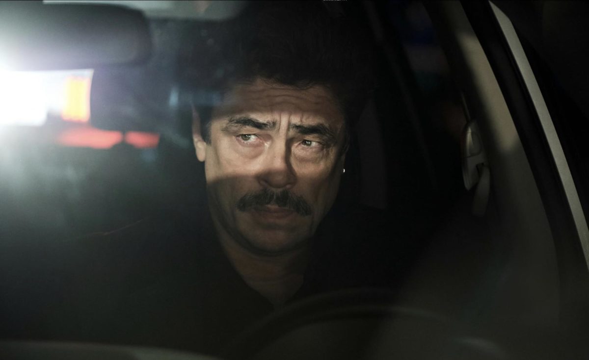 Tom Nichols, portrayed by Benicio del Toro, looks on in his car as he waits for someone outside their house.