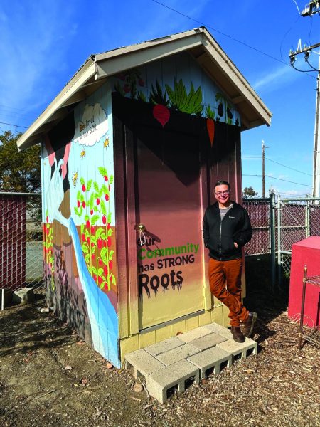 Art Professor Eric Sanchez stands for a photo adjacent to the freshly painted Rivertown Barn.