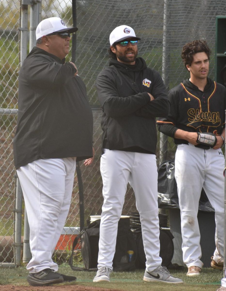 Head Coach Harmen Sidhu (center) discusses strategy with assistant coach Cliff Coleman as Colton Brooks watches game against Solano.