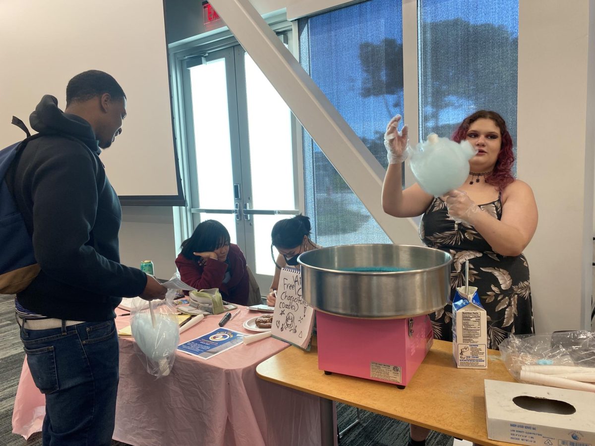 Angelica Bruno hands out cotton candy at the Art Club table during Club Carnival in the Student Union Conference Center Feb. 27.