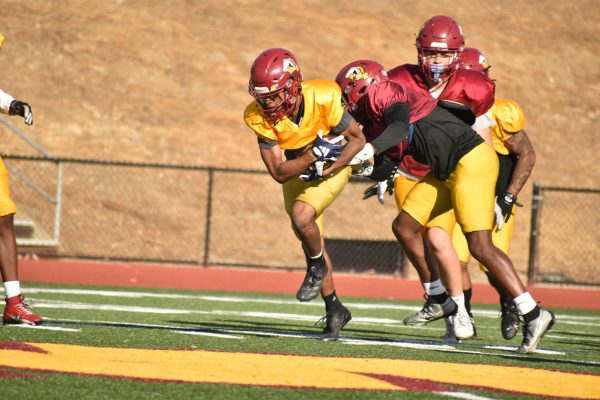 After catching a pass, a Mustangs' receiver holds on to the ball as defenders try to strip it away.