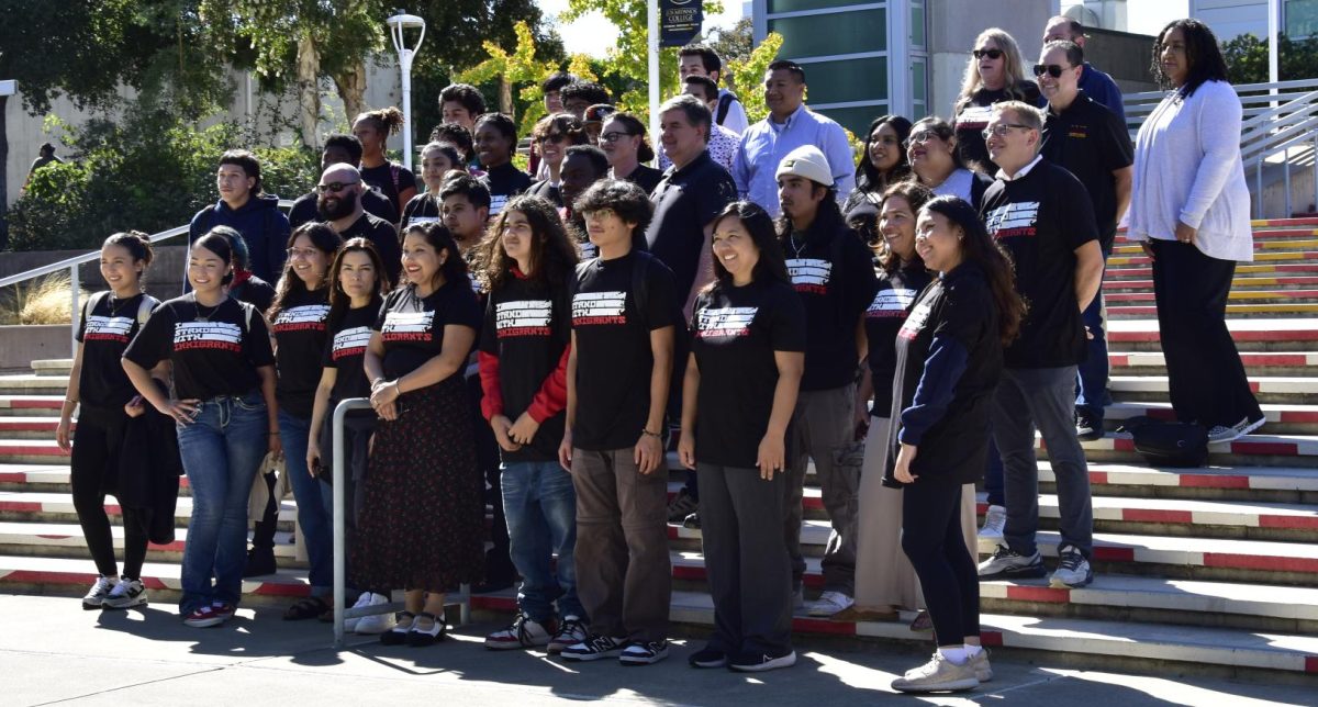 Attendees of "I stand with immigrants" pose for photo on quad steps.