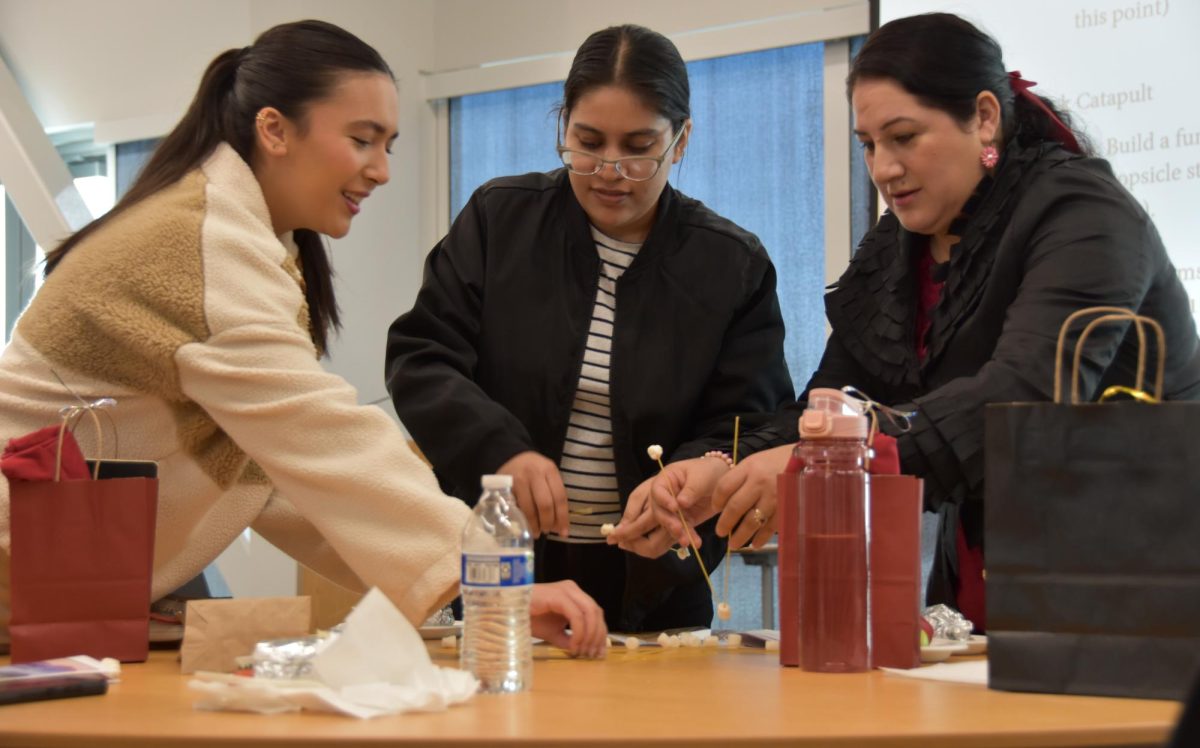 Students Brianna Luna, Silviady Vanegas and Maria Vill Martinez work together to make a spaghetti and marshmallow bridge during the team building activity at the Impact Conference, Nov. 8.