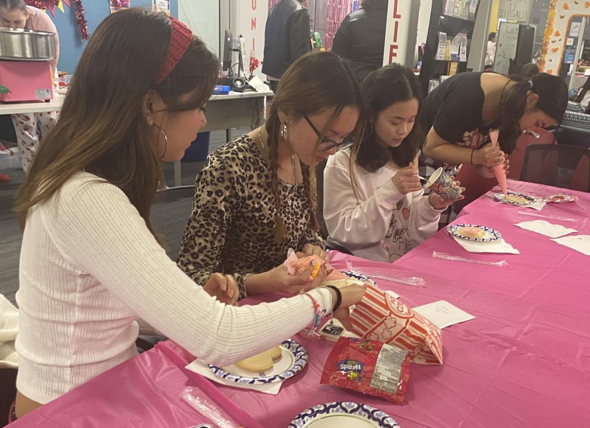 Group of students participate in cookie decorating activity at Galentine's Day event.