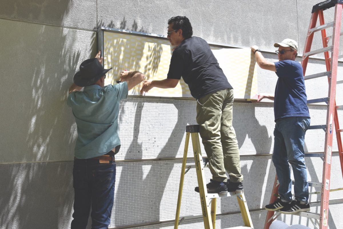 Nick Nabas, Cesar Reyes and John Schall install the new mural for graduates.