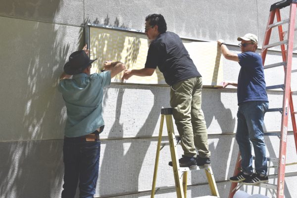 Nick Nabas, Cesar Reyes and John Schall install the new mural for graduates.