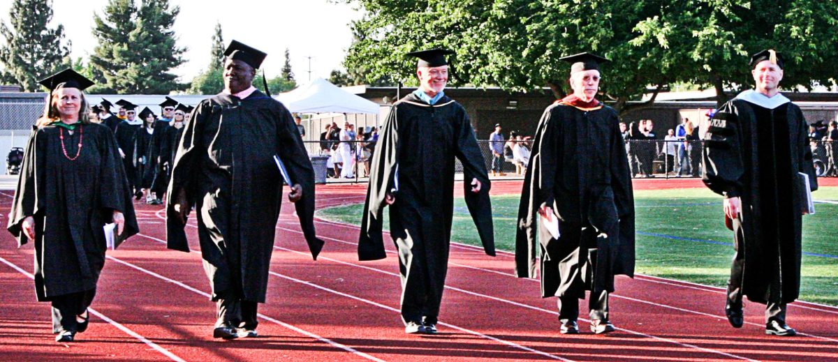 Former LMC President Bob Kratochvil is flanked by college and district leadership as they march into the football stadium for graduation in 2014.