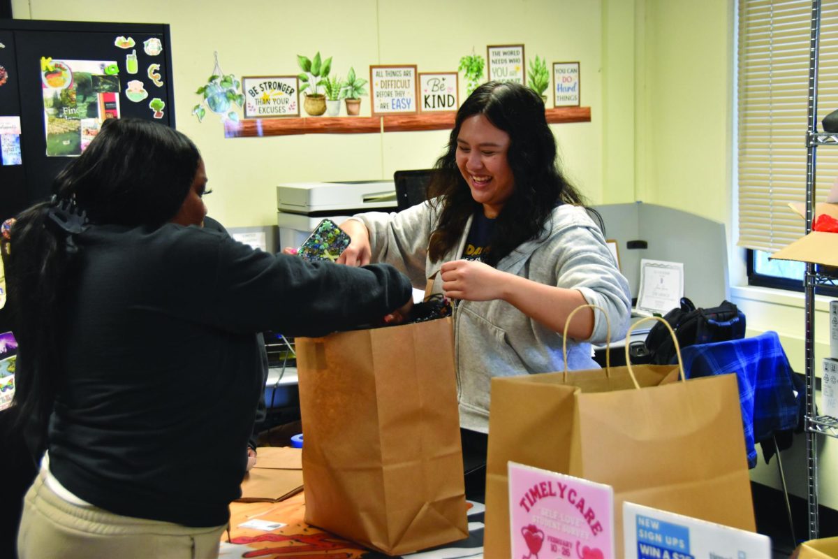 Cheyenne Phan helps fill a grocery bag in the LMC Marketplace during the CalFresh event.