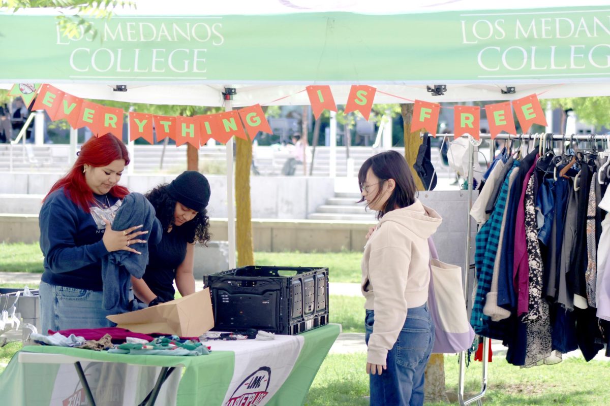 Marketplace staff member Tatiana Rodriguez and Puente member Vanessa Amaya bag student Charlize Almazan's free clothes. 
