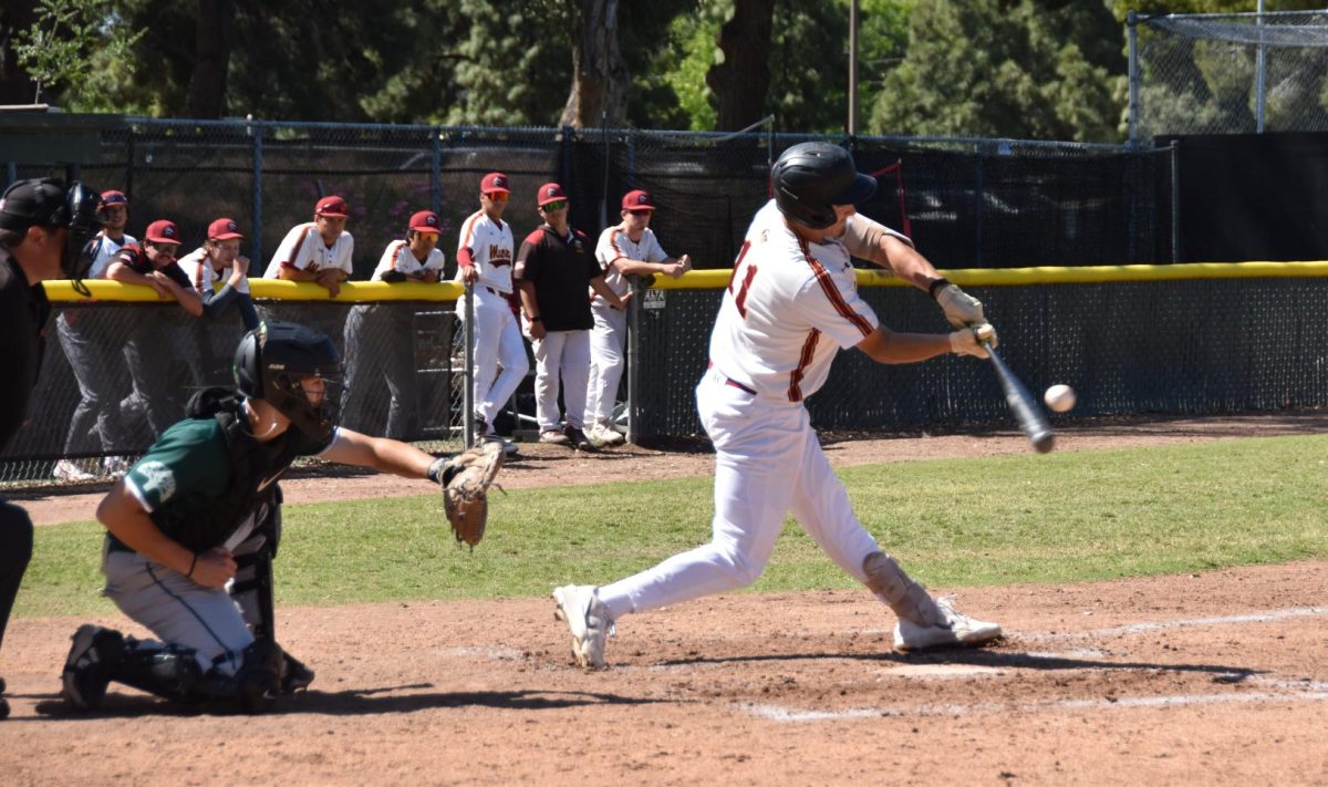 Batter No. 11 Carlos Garcia at home base swinging and connecting with the ball to send it left field during the April 14 game.